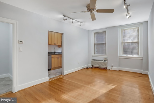 unfurnished living room featuring a wall mounted air conditioner, ceiling fan, light hardwood / wood-style floors, and sink