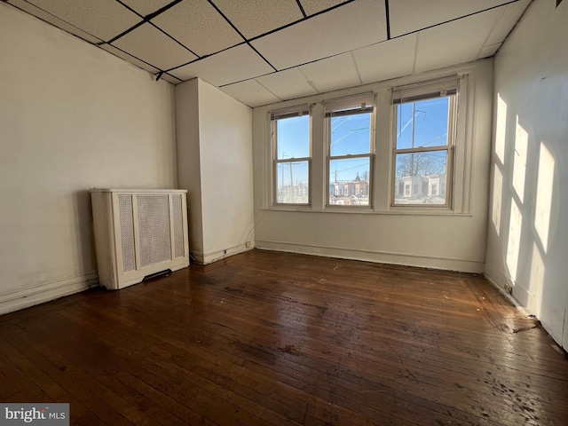 empty room featuring dark hardwood / wood-style flooring and a drop ceiling