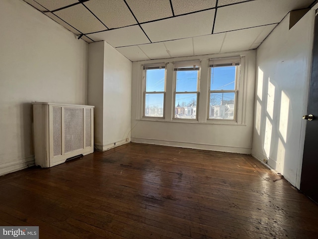 spare room featuring radiator, dark hardwood / wood-style flooring, and a drop ceiling