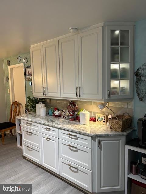 kitchen featuring white cabinets, tasteful backsplash, light stone counters, and light hardwood / wood-style flooring