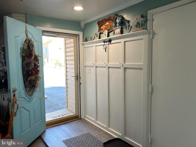 doorway with light wood-type flooring and crown molding