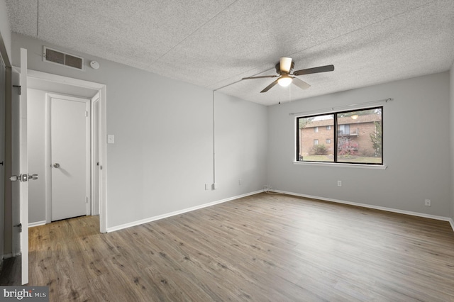 empty room with ceiling fan, hardwood / wood-style floors, and a textured ceiling