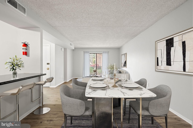 dining space with hardwood / wood-style floors and a textured ceiling