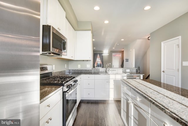 kitchen featuring white cabinets, sink, stainless steel appliances, and dark stone counters