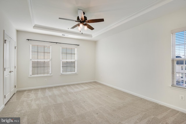 carpeted spare room featuring a tray ceiling, crown molding, and ceiling fan