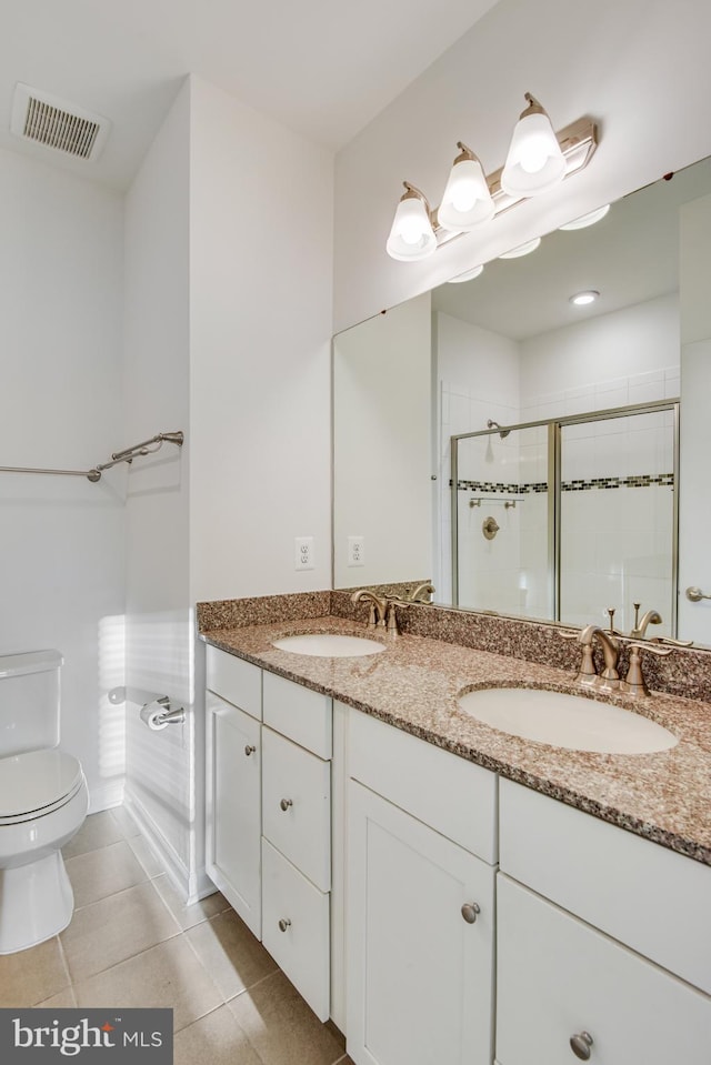 bathroom with tile patterned flooring, vanity, toilet, and walk in shower