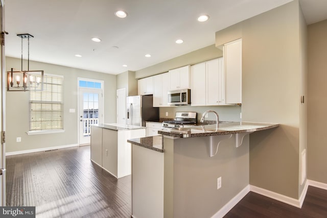 kitchen featuring kitchen peninsula, hanging light fixtures, white cabinets, and stainless steel appliances