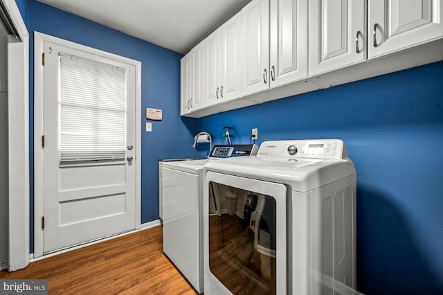 laundry area with cabinets, hardwood / wood-style flooring, and washing machine and clothes dryer