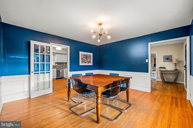 dining area with light hardwood / wood-style floors and an inviting chandelier