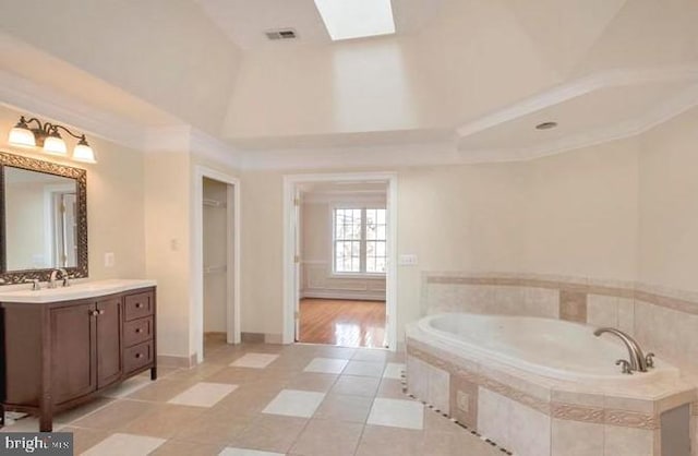 6614 Quander Rd, Alexandria, VA 22307 - bathroom with tile patterned floors, vanity, vaulted ceiling with skylight, and a relaxing tiled tub