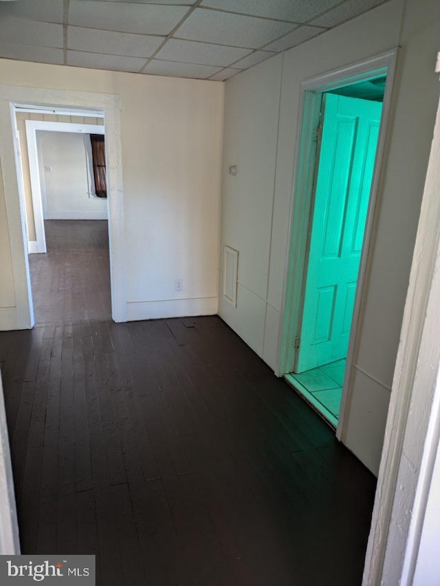 unfurnished room with a drop ceiling and dark wood-type flooring