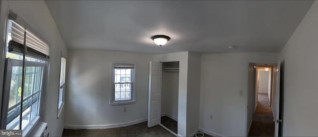 unfurnished bedroom featuring dark carpet and a closet