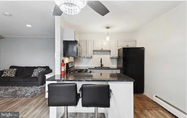 kitchen featuring a kitchen bar, a baseboard heating unit, sink, black appliances, and pendant lighting