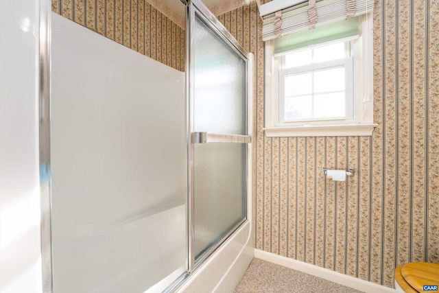 bathroom featuring toilet and combined bath / shower with glass door