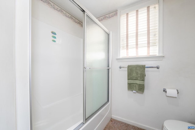 bathroom featuring combined bath / shower with glass door and toilet