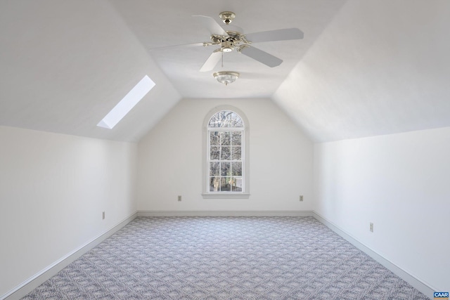 bonus room with ceiling fan, vaulted ceiling with skylight, and light colored carpet