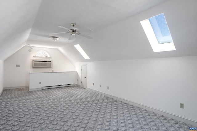 additional living space featuring a wall mounted air conditioner, vaulted ceiling with skylight, ceiling fan, a baseboard radiator, and light colored carpet