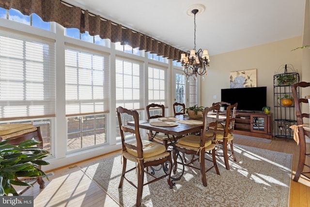 dining room with hardwood / wood-style floors and an inviting chandelier