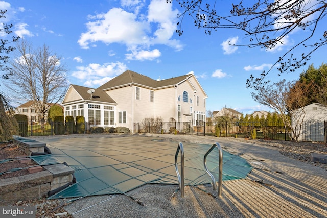 rear view of property with a sunroom, a patio, and a covered pool