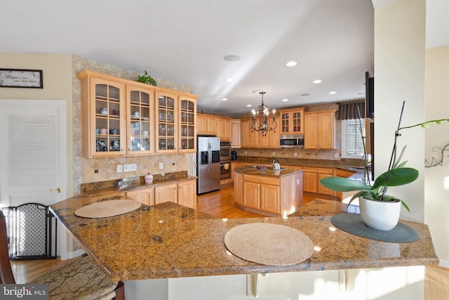 kitchen featuring decorative light fixtures, a center island, light hardwood / wood-style floors, and appliances with stainless steel finishes