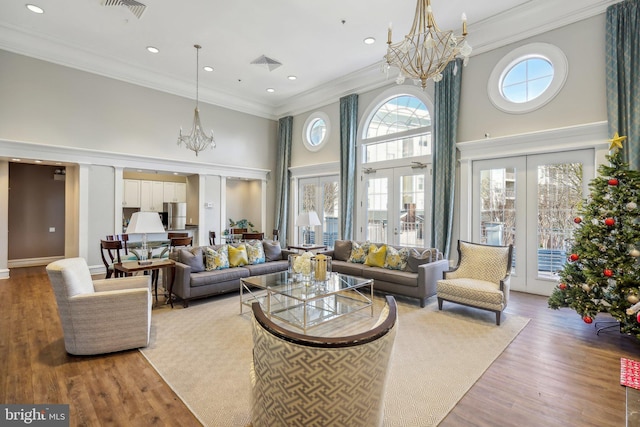 living room featuring crown molding, french doors, wood-type flooring, and a high ceiling