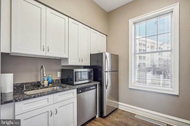 1645 International Dr Unit 121, Mclean, VA 22102 - kitchen with appliances with stainless steel finishes, white cabinetry, dark wood-type flooring, and dark stone countertops