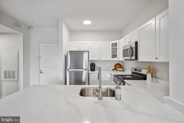 1645 International Dr Unit 121, Mclean, VA 22102 - kitchen featuring stainless steel appliances, glass insert cabinets, light stone countertops, and white cabinetry