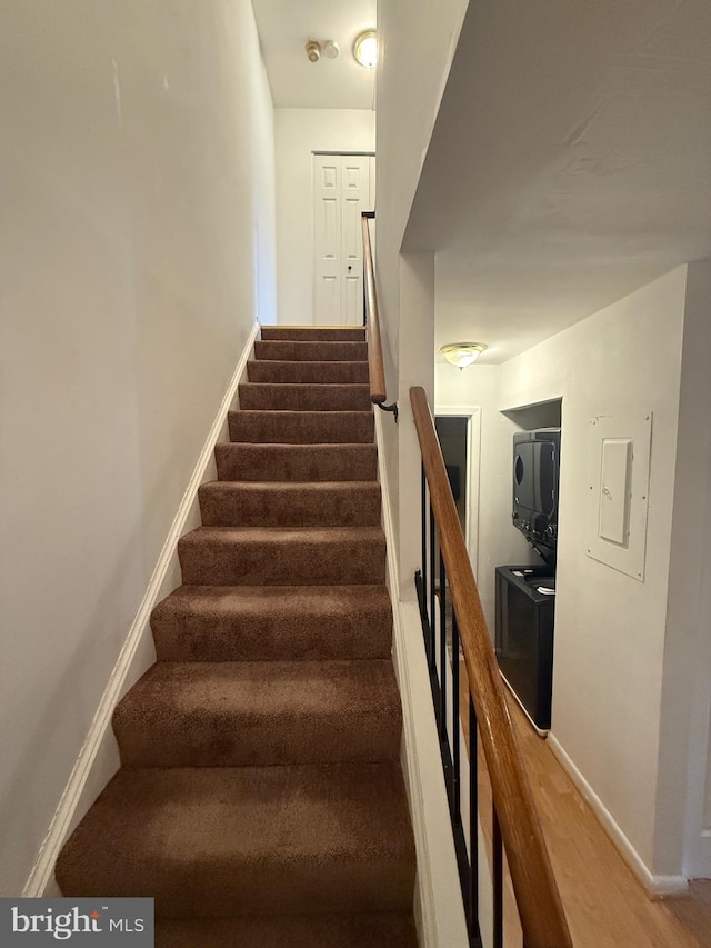 stairs featuring electric panel and wood-type flooring