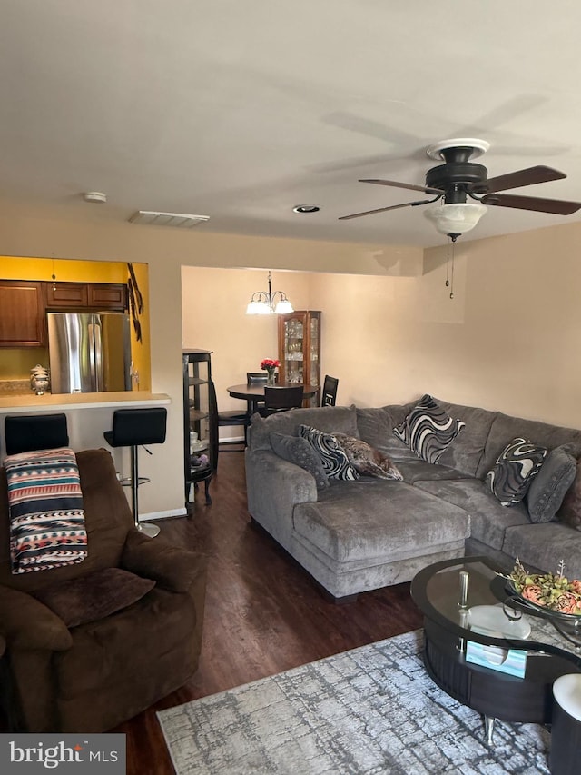 living room with dark hardwood / wood-style flooring and ceiling fan with notable chandelier