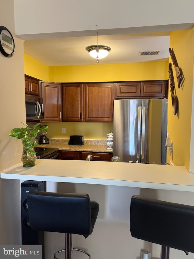 kitchen featuring a breakfast bar area, kitchen peninsula, and appliances with stainless steel finishes