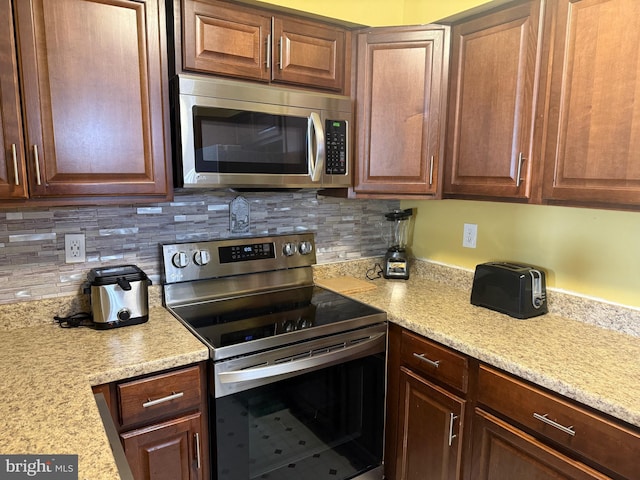 kitchen with decorative backsplash, light stone counters, and stainless steel appliances