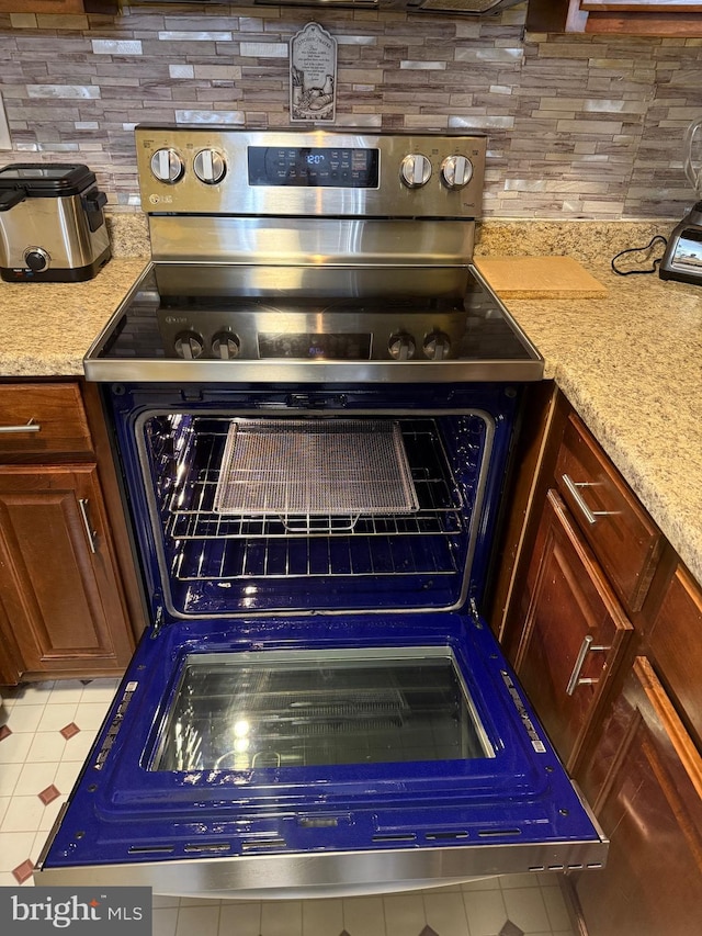 details featuring decorative backsplash, stainless steel electric range oven, and light stone counters