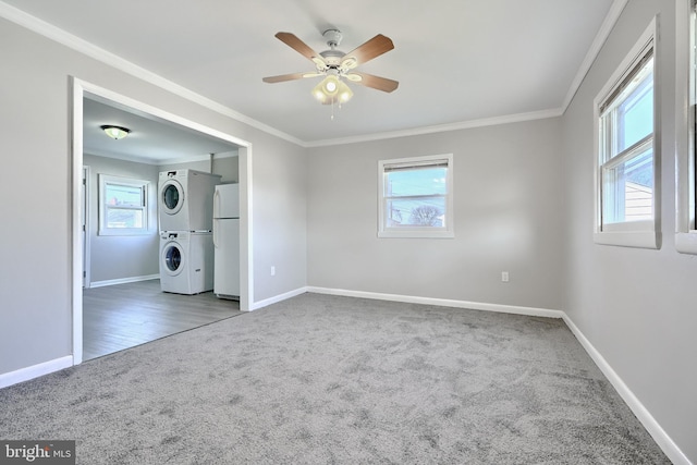 interior space featuring carpet flooring, stacked washer / dryer, ceiling fan, and crown molding