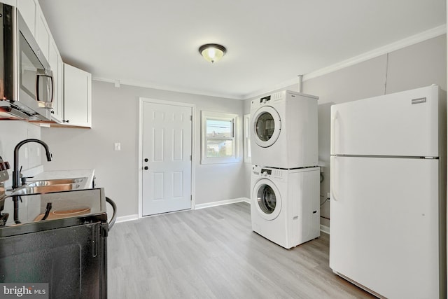 laundry room featuring crown molding, sink, light hardwood / wood-style floors, and stacked washer / drying machine