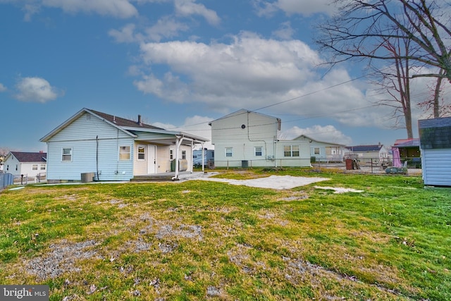 rear view of house featuring central AC and a lawn