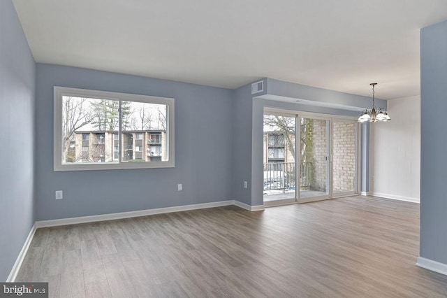 spare room with hardwood / wood-style floors and a notable chandelier