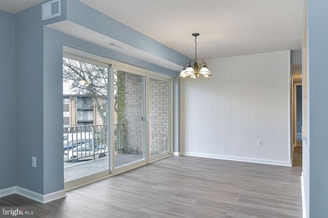 unfurnished dining area with wood-type flooring and a chandelier