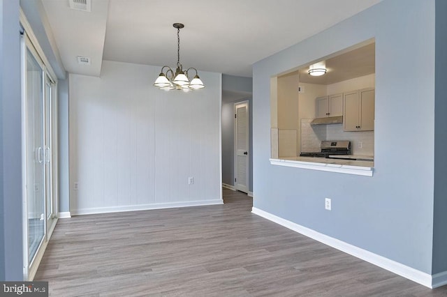 kitchen featuring light wood-type flooring, tasteful backsplash, an inviting chandelier, stainless steel range oven, and hanging light fixtures