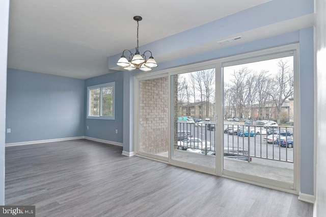 unfurnished dining area with wood-type flooring and a chandelier