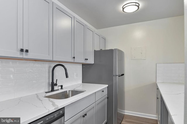 kitchen featuring light stone countertops, decorative backsplash, stainless steel appliances, dark wood-type flooring, and sink