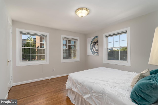 bedroom with hardwood / wood-style floors and multiple windows