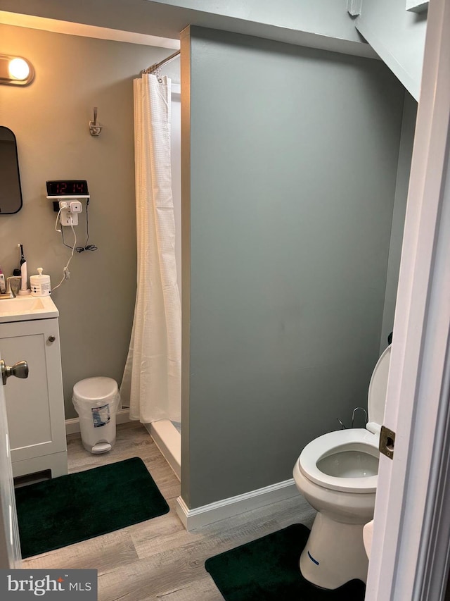 bathroom with a shower with curtain, vanity, hardwood / wood-style flooring, and toilet