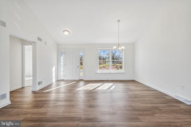 foyer entrance with dark hardwood / wood-style floors, high vaulted ceiling, and an inviting chandelier