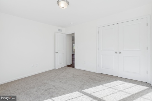 unfurnished bedroom featuring a closet and light colored carpet