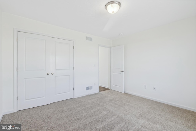 unfurnished bedroom with light carpet and a closet