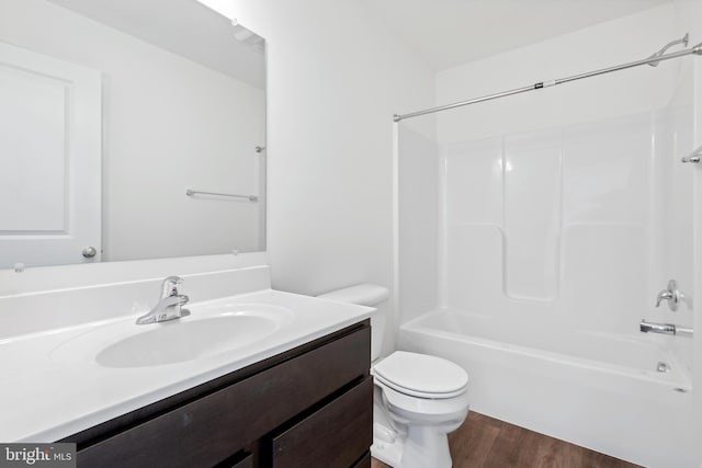 full bathroom with hardwood / wood-style floors, vanity, shower / bathtub combination, and toilet