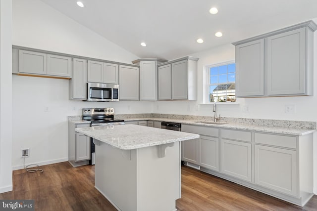 kitchen featuring appliances with stainless steel finishes, dark hardwood / wood-style flooring, vaulted ceiling, sink, and a center island