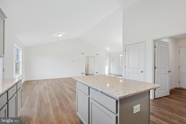 kitchen featuring gray cabinets, a center island, light hardwood / wood-style floors, and lofted ceiling