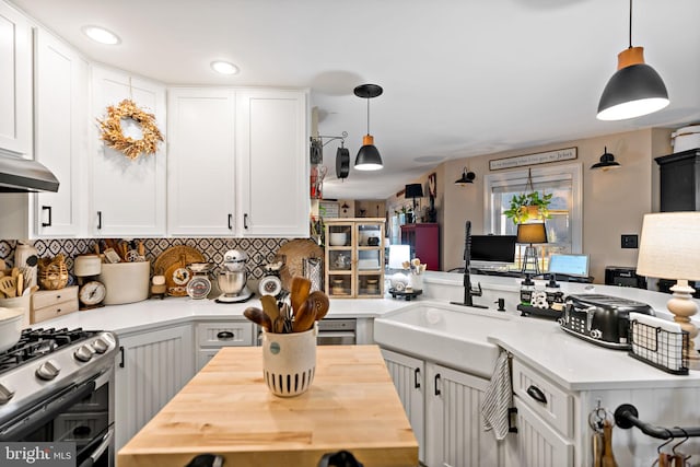 kitchen with gas range, decorative light fixtures, white cabinetry, and sink