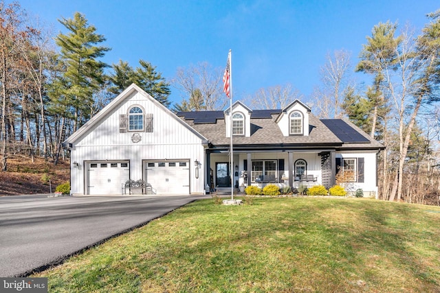 view of front of house featuring solar panels, a front lawn, covered porch, and a garage